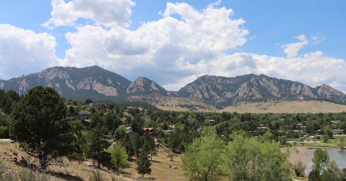 Scenic landscape of Boulder, Colorado with the Rocky Mountains under a blue sky.